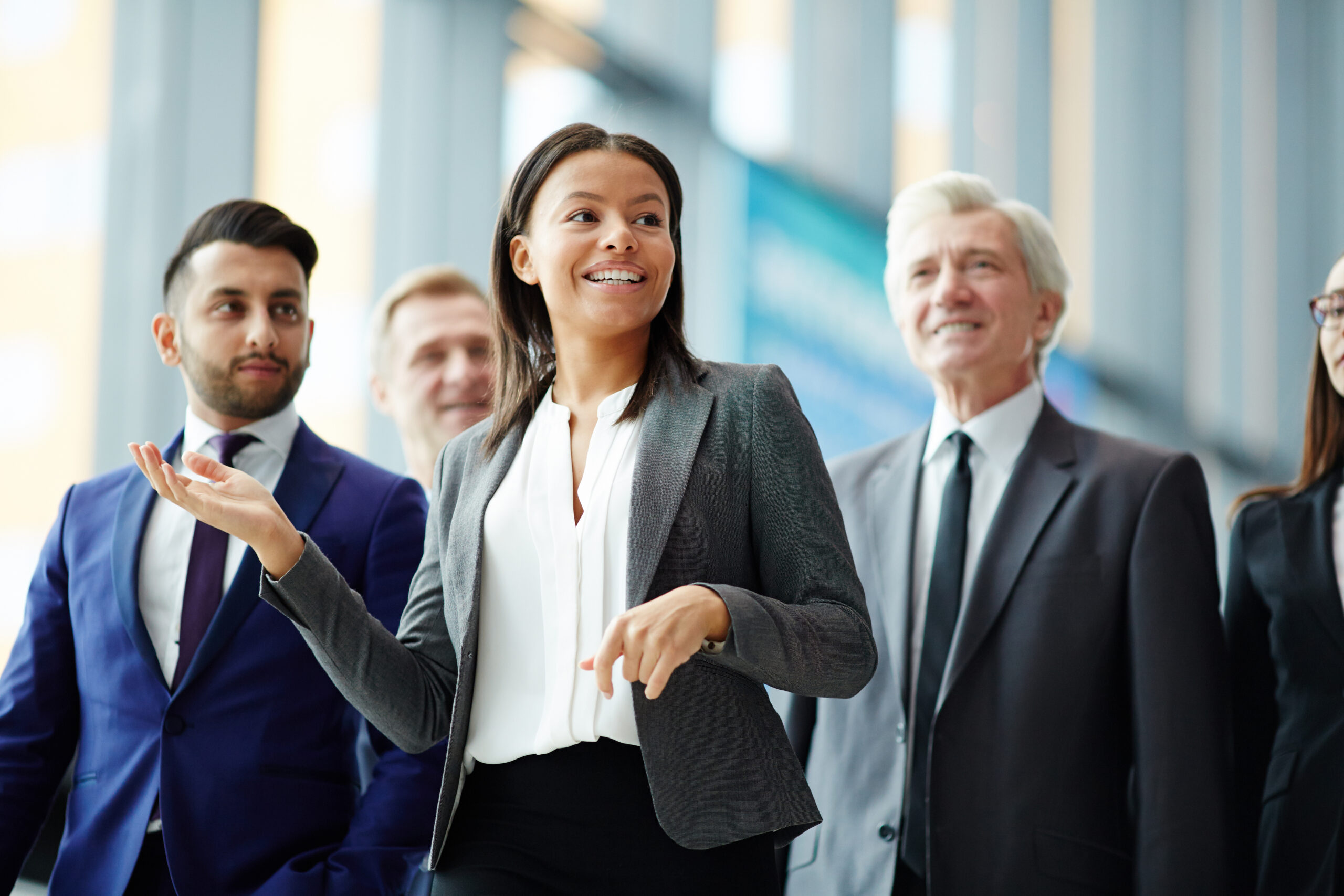 A businesswoman guiding a group of corporate executives in her office.